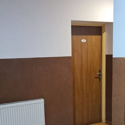 Korytarz z drewnianymi drzwiami do pokoju numer 5