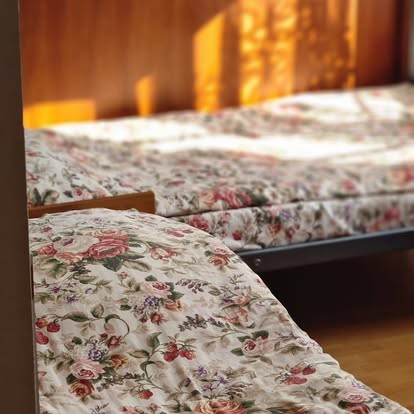 Pojedyncze łóżka w pokoju Villa Victoria, kwieciste narzuty i drewniany zagłówek