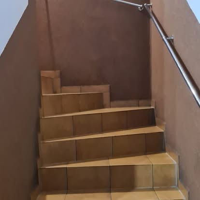 Klatka schodowa wyłożona płytkami, ze stalową poręczą